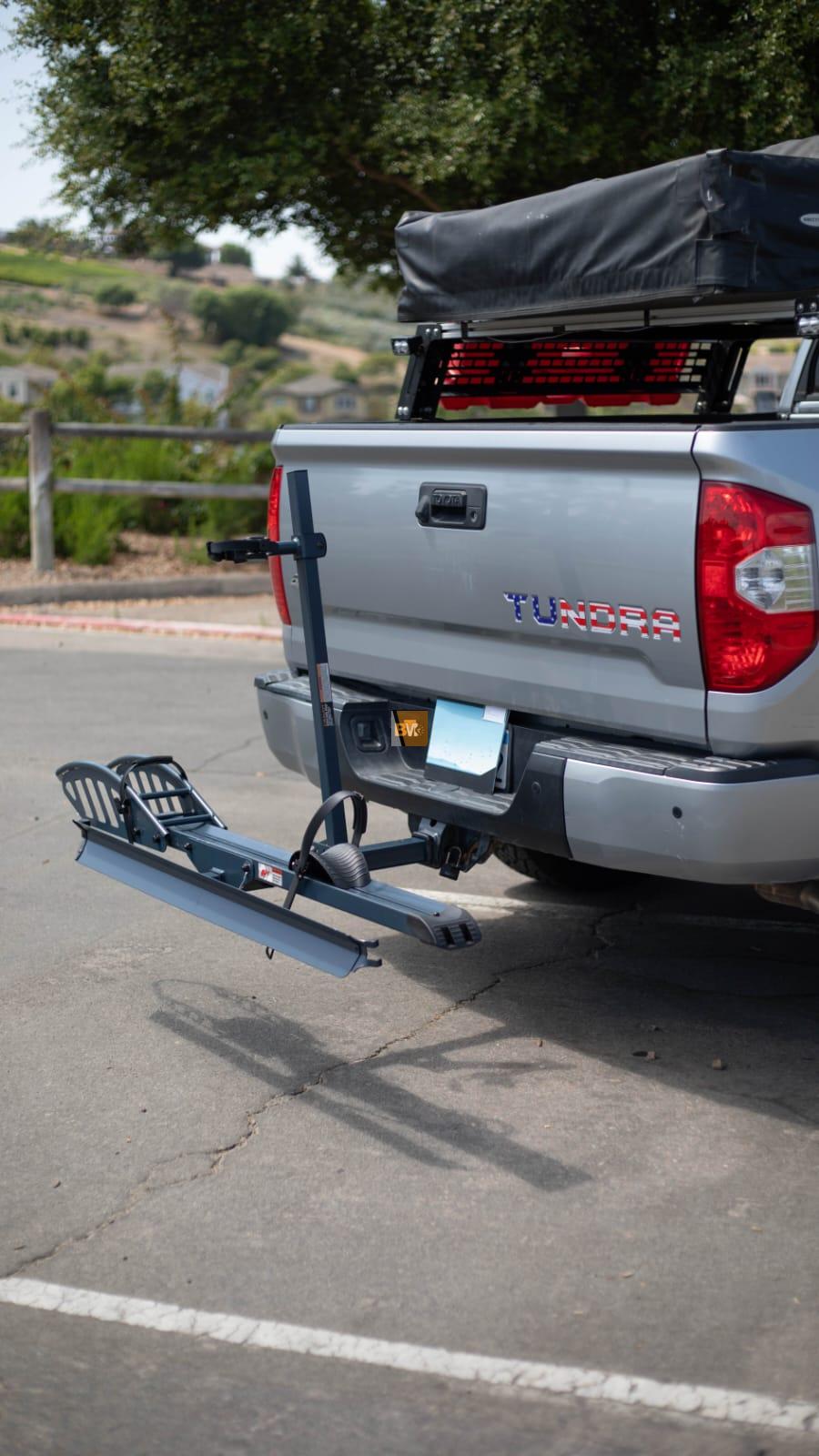 An eBike securely mounted on a rear hitch rack positioned on a car.